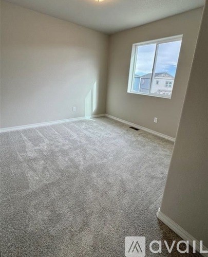 A room with a carpeted floor and a window showing a building outside.