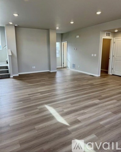 A spacious room with wooden flooring and white walls.
