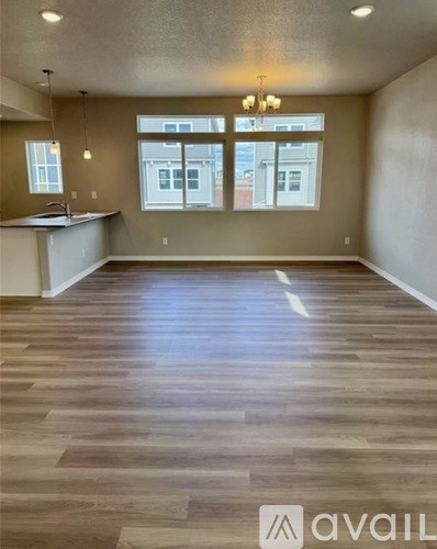 A spacious room with wooden flooring and a kitchen area.