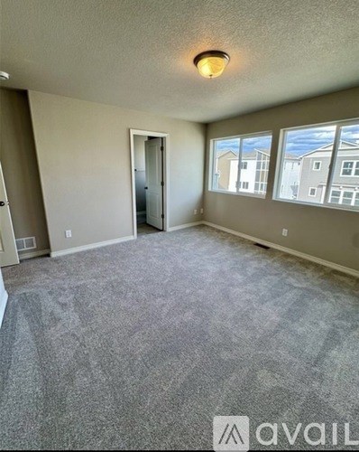 A room with a carpeted floor and a window overlooking other buildings.