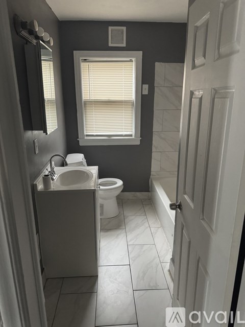 A bathroom with a toilet, sink, and mirror.
