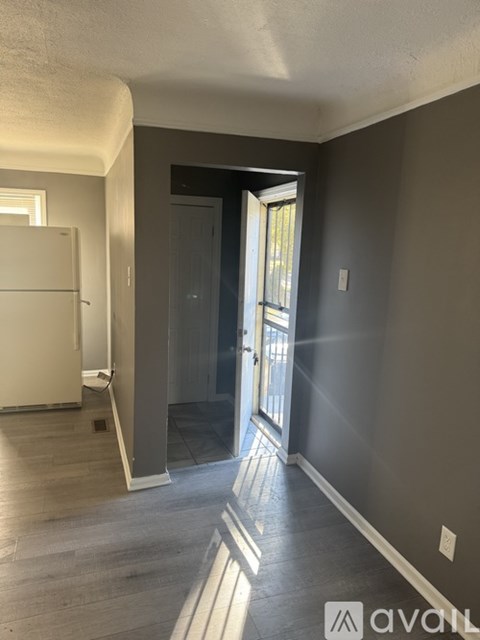 A room with a white fridge and wooden flooring.