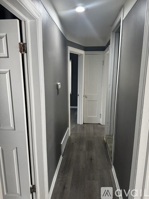 A hallway with white doors and a wooden floor.