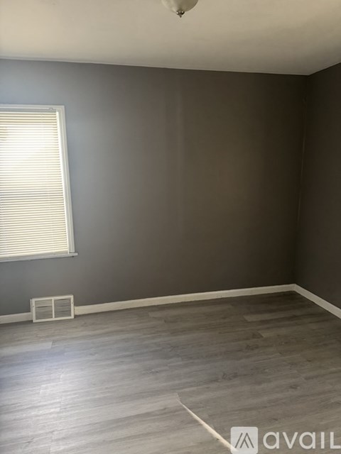 A room with a grey wall and a window with blinds.