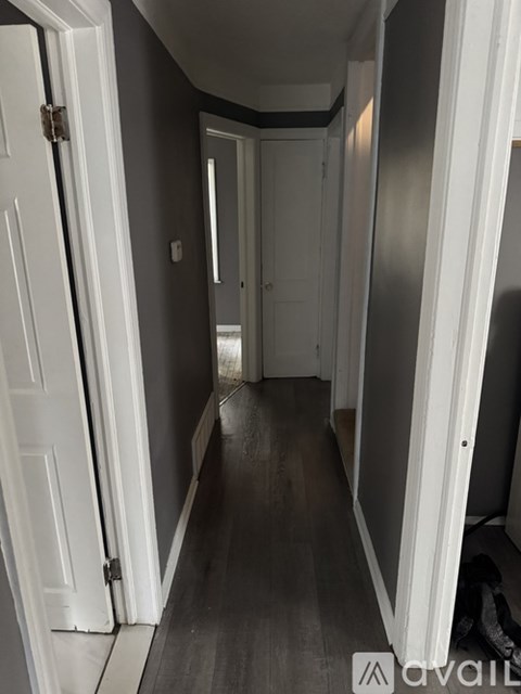 A hallway with white doors and a white door on the left.