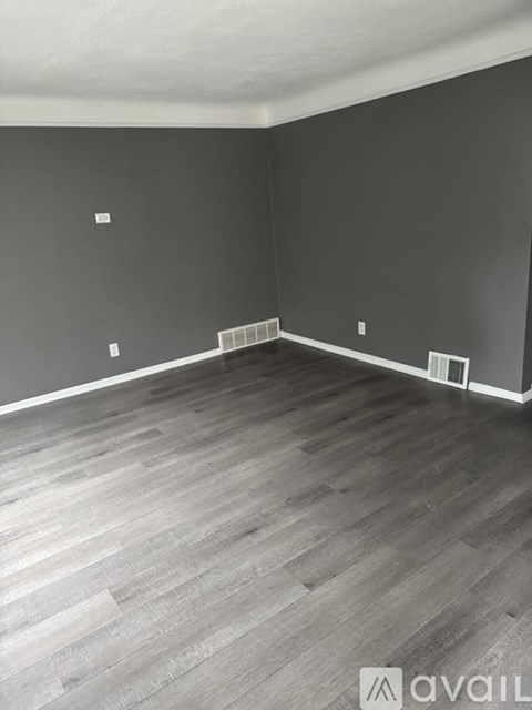 A room with grey flooring and dark walls.