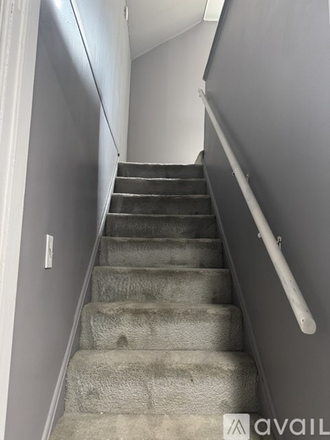 A staircase with a grey carpeted runner and white handrail.