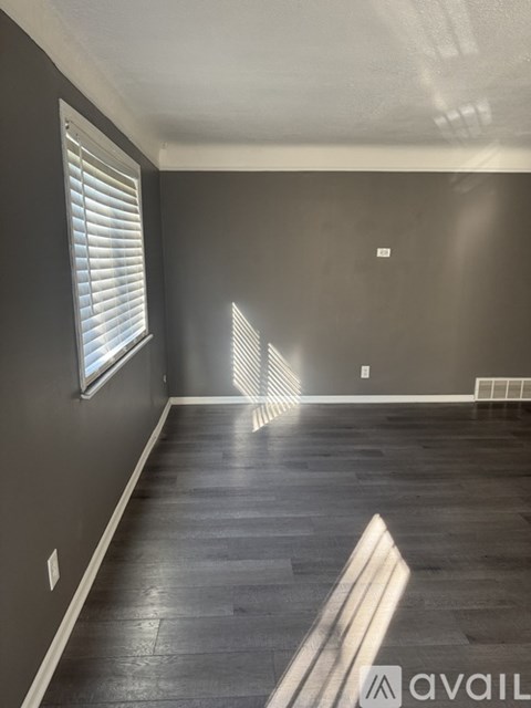 A room with wooden flooring and a window with blinds.