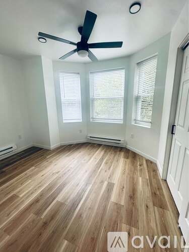 A room with wooden flooring and a ceiling fan.