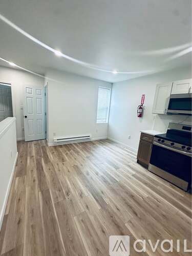 A kitchen with wooden flooring and a stove top oven.