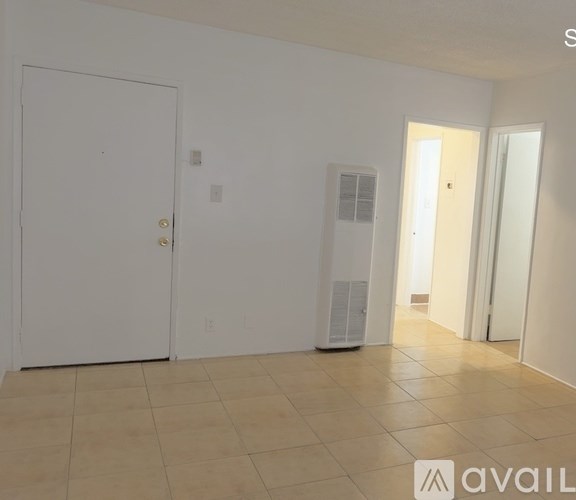 A room with a white door, a white wall, and a white floor.