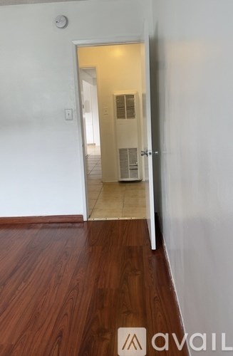 A hallway with a wooden floor and a white wall.