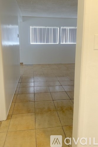 A room with tiled flooring and a window with blinds.