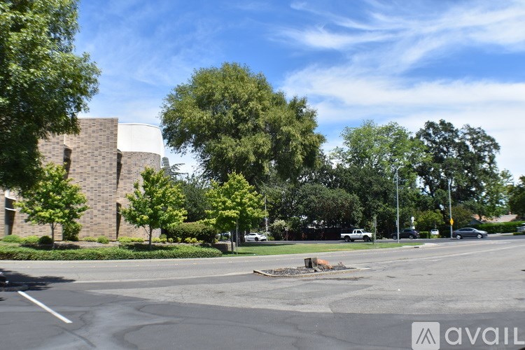 A parking lot with a building and trees in the background.