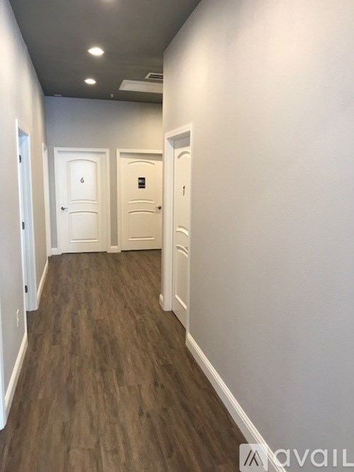 A hallway with three doors and wooden floors.