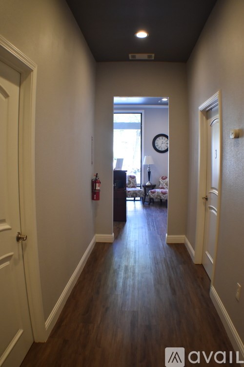 A hallway with a clock on the wall and a door on the left.
