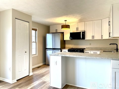 A kitchen with white cabinets and a black fridge.