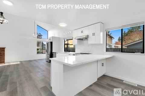 A modern kitchen with white cabinets and a large island is available for rent.