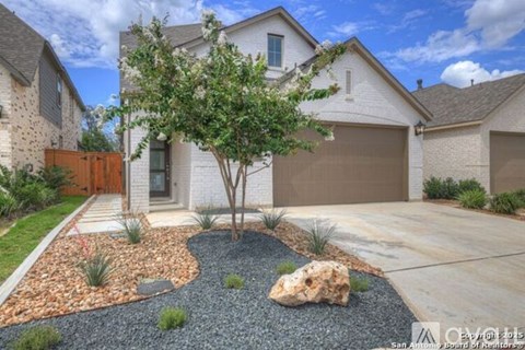 A house with a brown garage door and a tree in front.