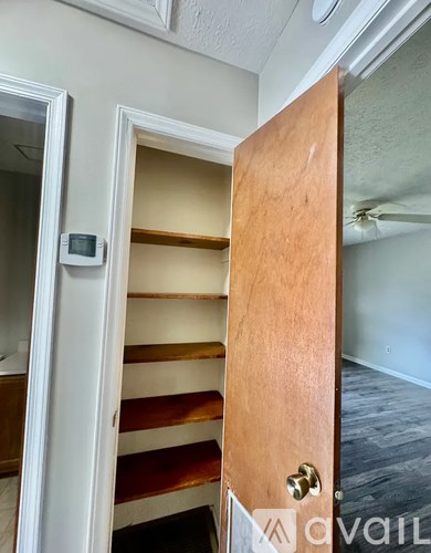 A white door with a wooden door handle and a small square device on the wall.