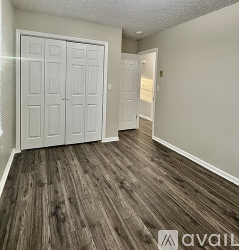 A room with a white door and a wooden floor.
