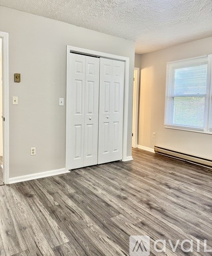 A room with a white door and wooden flooring.