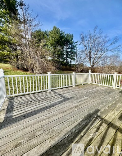A wooden deck with a white railing and trees in the background.