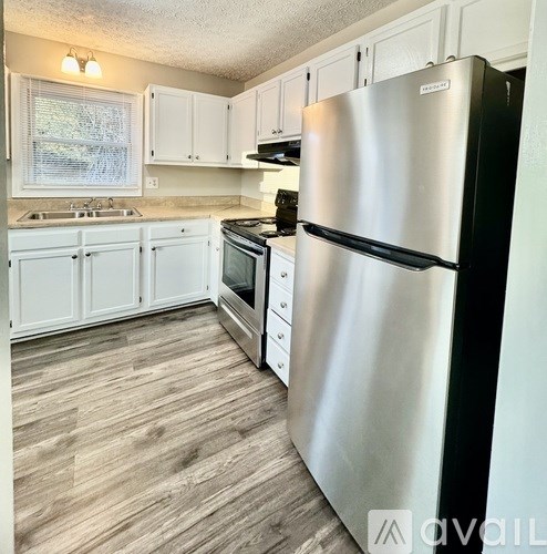 A kitchen with a stainless steel refrigerator and wooden flooring.