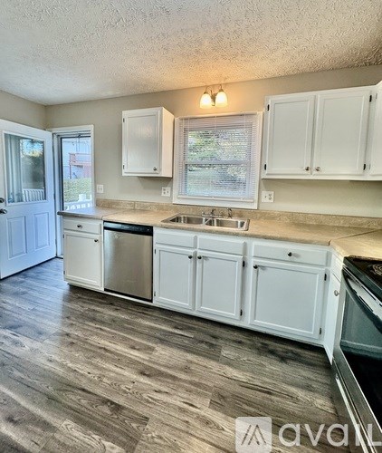 A kitchen with white cabinets and a wooden floor.