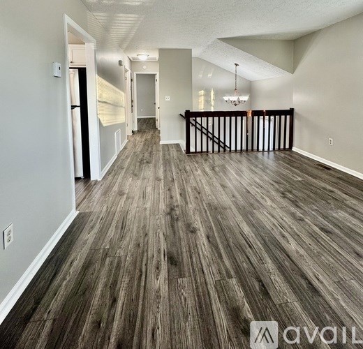 A spacious room with wooden flooring and a staircase.