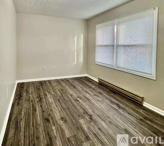 A room with wooden flooring and a window with blinds.