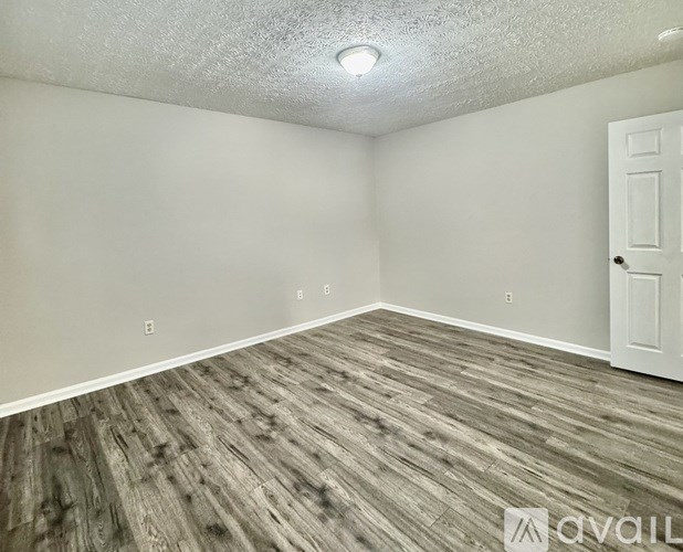 A room with wooden flooring and a white door.