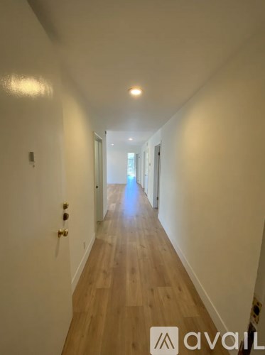 A long hallway with wooden floors and white walls.