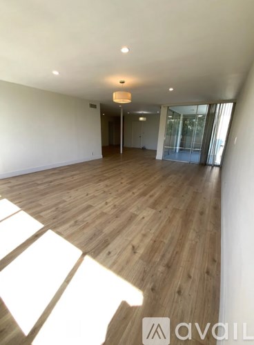 A spacious room with wooden flooring and a large window.