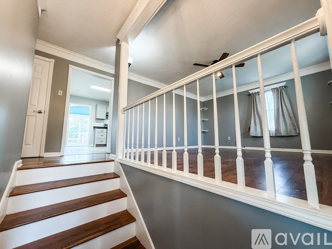 A staircase with a ceiling fan and a window with curtains.
