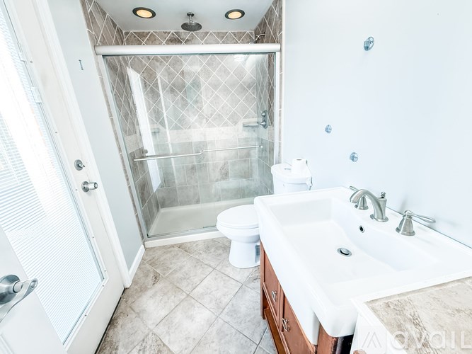 A room with a ceiling fan and sliding glass doors leading to a balcony.