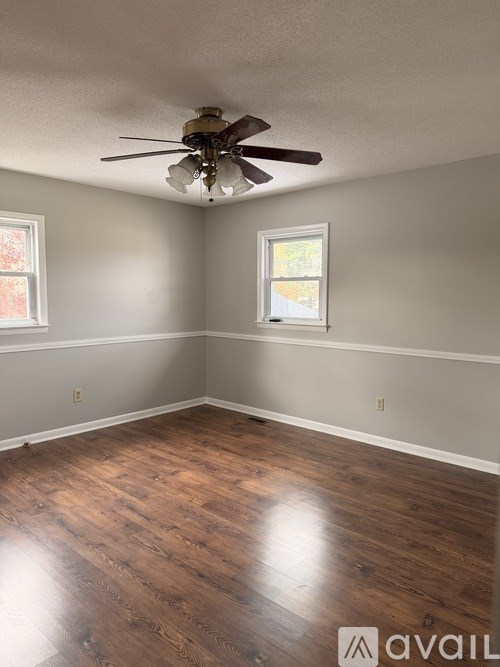 A room with a ceiling fan and wood flooring.