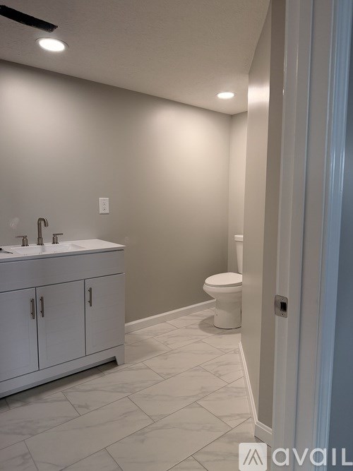 A bathroom with a toilet, sink, and cabinet.