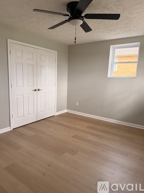 A room with a white door and a ceiling fan.