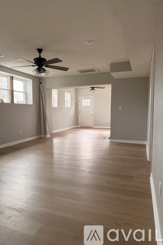 A room with a ceiling fan and wooden flooring.