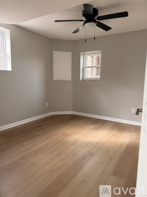 A room with a ceiling fan and wooden flooring.