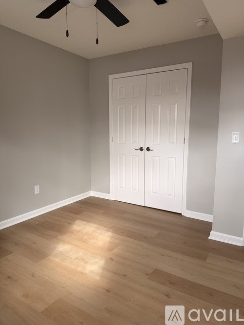 A room with a white door and wooden flooring.