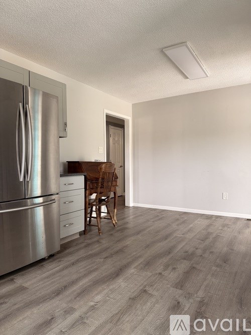 A kitchen with a stainless steel refrigerator and wooden flooring.