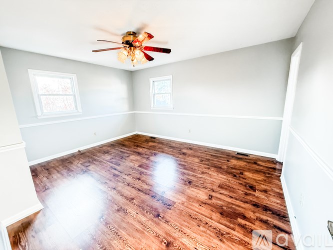 A room with a ceiling fan and sliding glass doors.