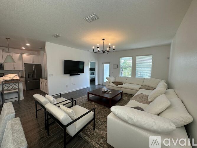 A living room with a white couch and a television on the wall.