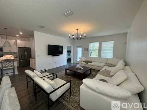A living room with a white couch and a television on the wall.