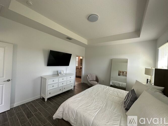 A bedroom with a large bed and a television on the wall.