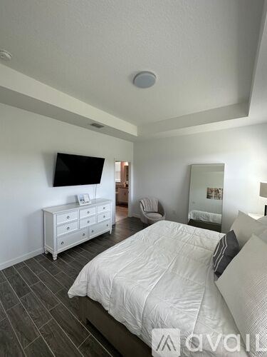 A bedroom with a bed, dresser, and television.