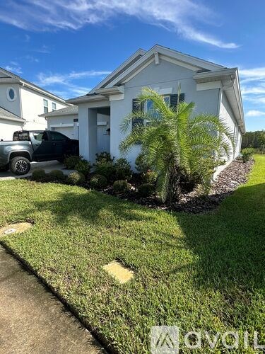 A white house with a green lawn and a black truck parked in front.