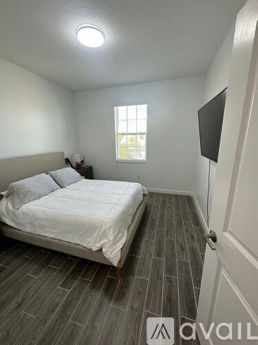 A bedroom with a bed, a window, and a door.